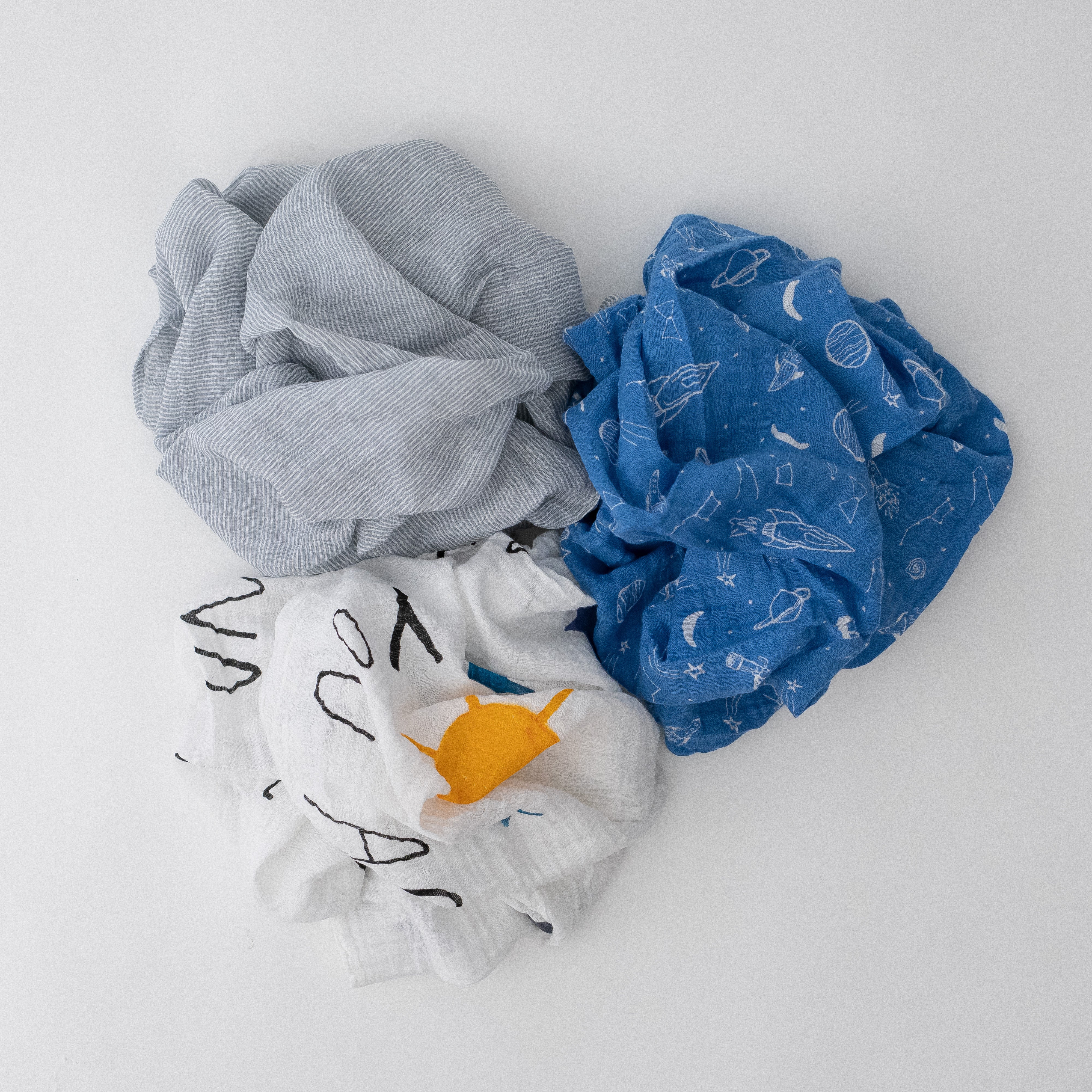 3 swaddle blankets featuring grey micro stripe, white background yellow sun and blue stars, and blue background with white space items