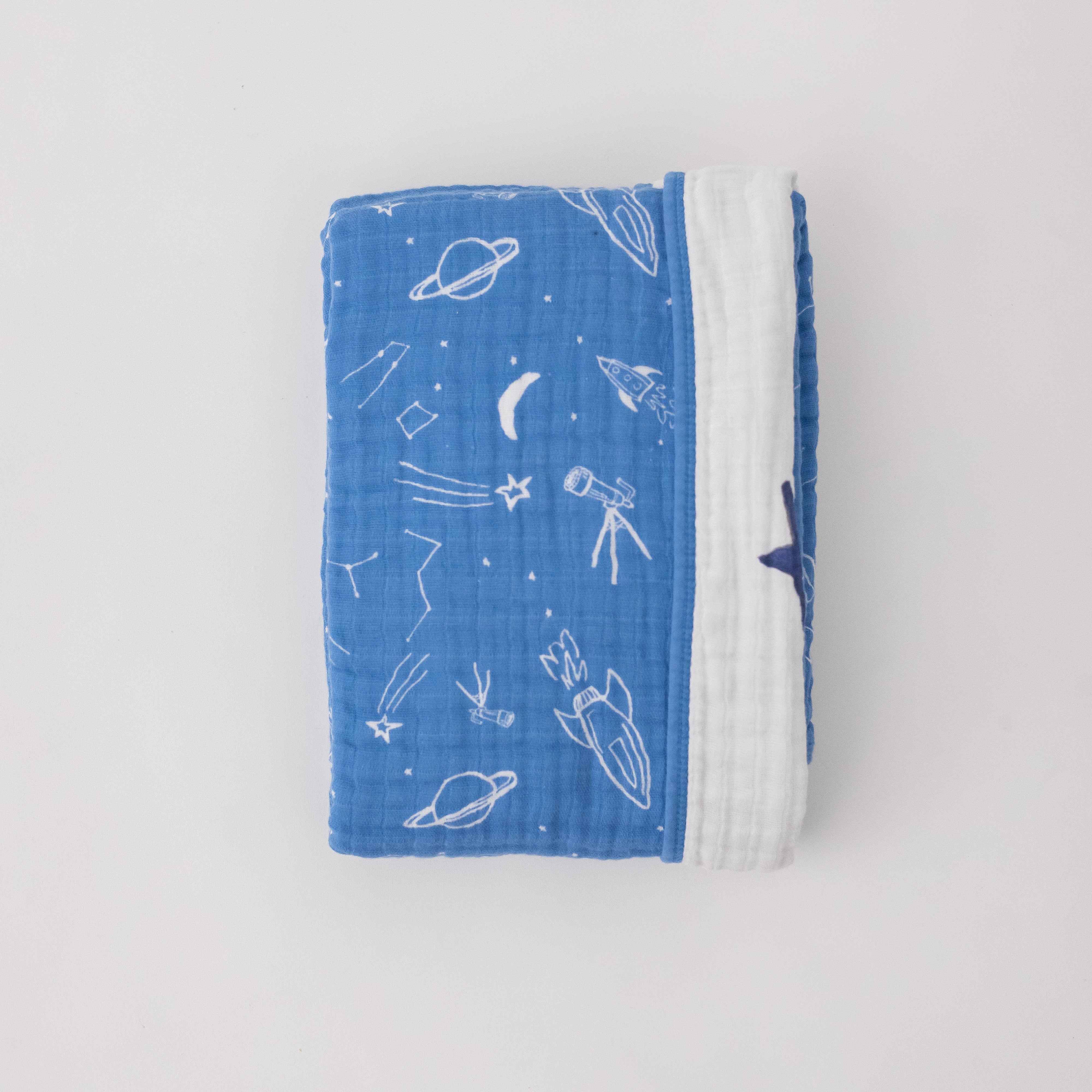 super soft cotton muslin quilt with white planets, stars, telescopes, and rocket ships all on a blue background on one side and the text "you are my sun my moon and all my stars" on the other side