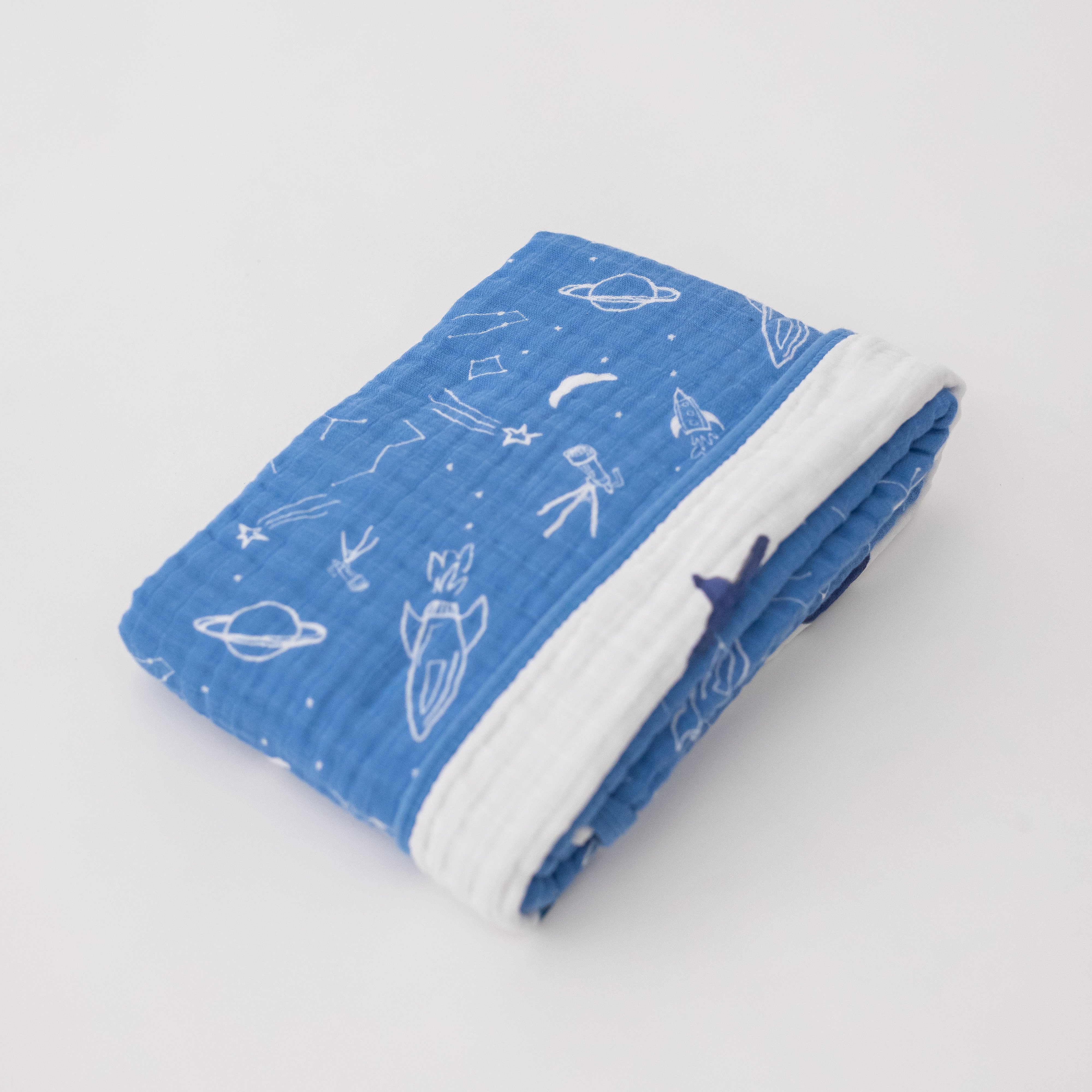 super soft cotton muslin quilt with white planets, stars, telescopes, and rocket ships all on a blue background on one side and the text "you are my sun my moon and all my stars" on the other side