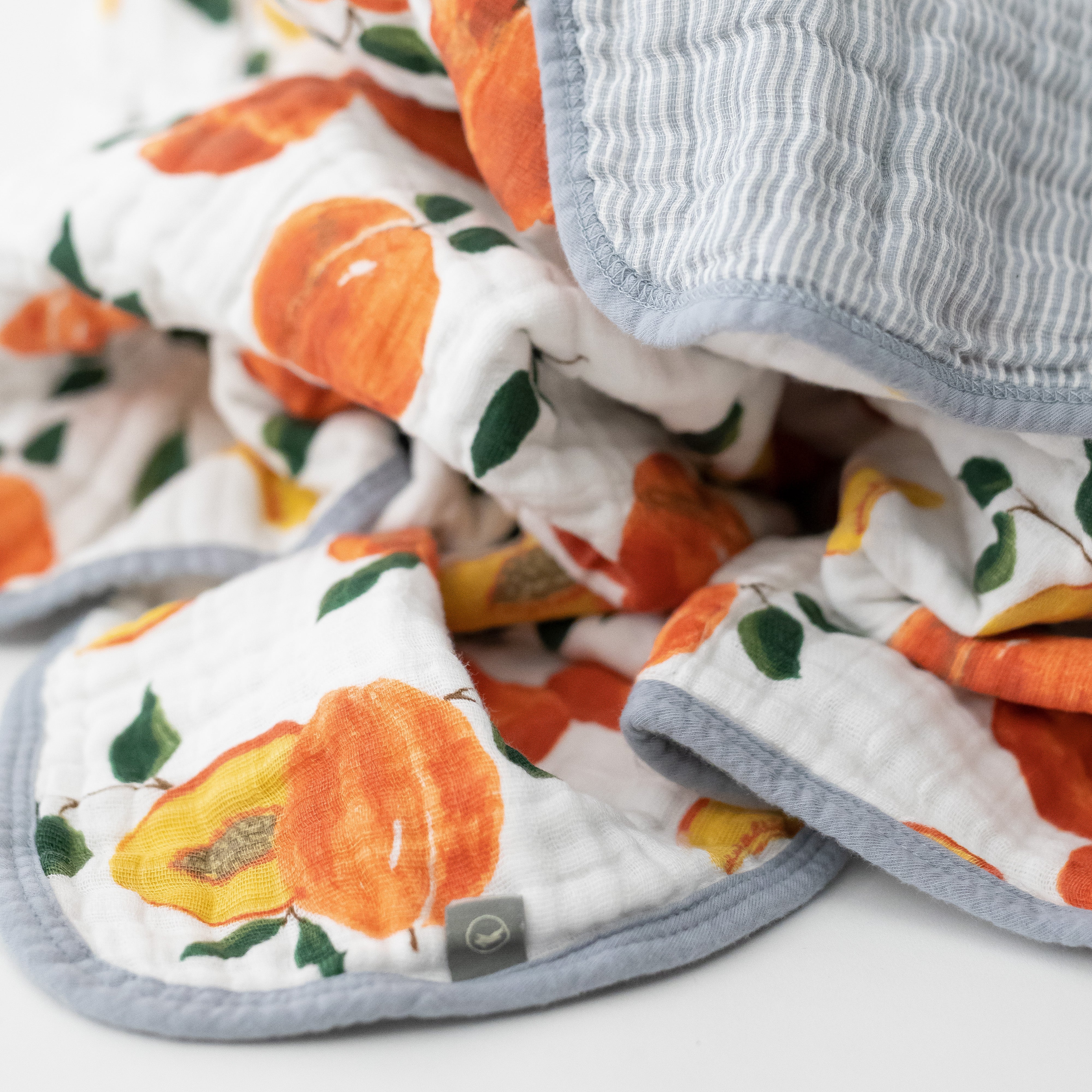 super soft cotton muslin quilt with whole and cut open peaches on one side and grey micro stripes on the other side