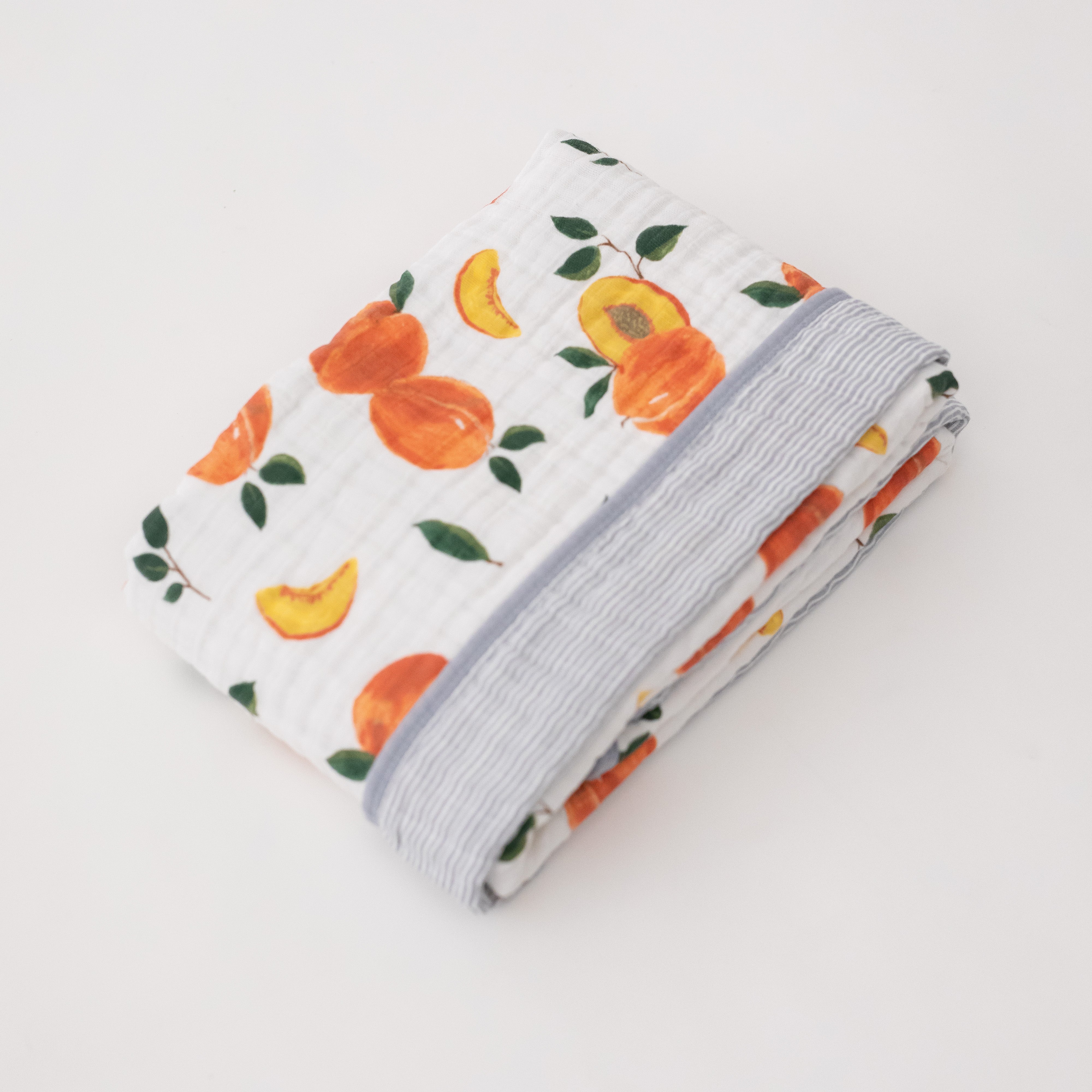 super soft cotton muslin quilt with whole and cut open peaches on one side and grey micro stripes on the other side
