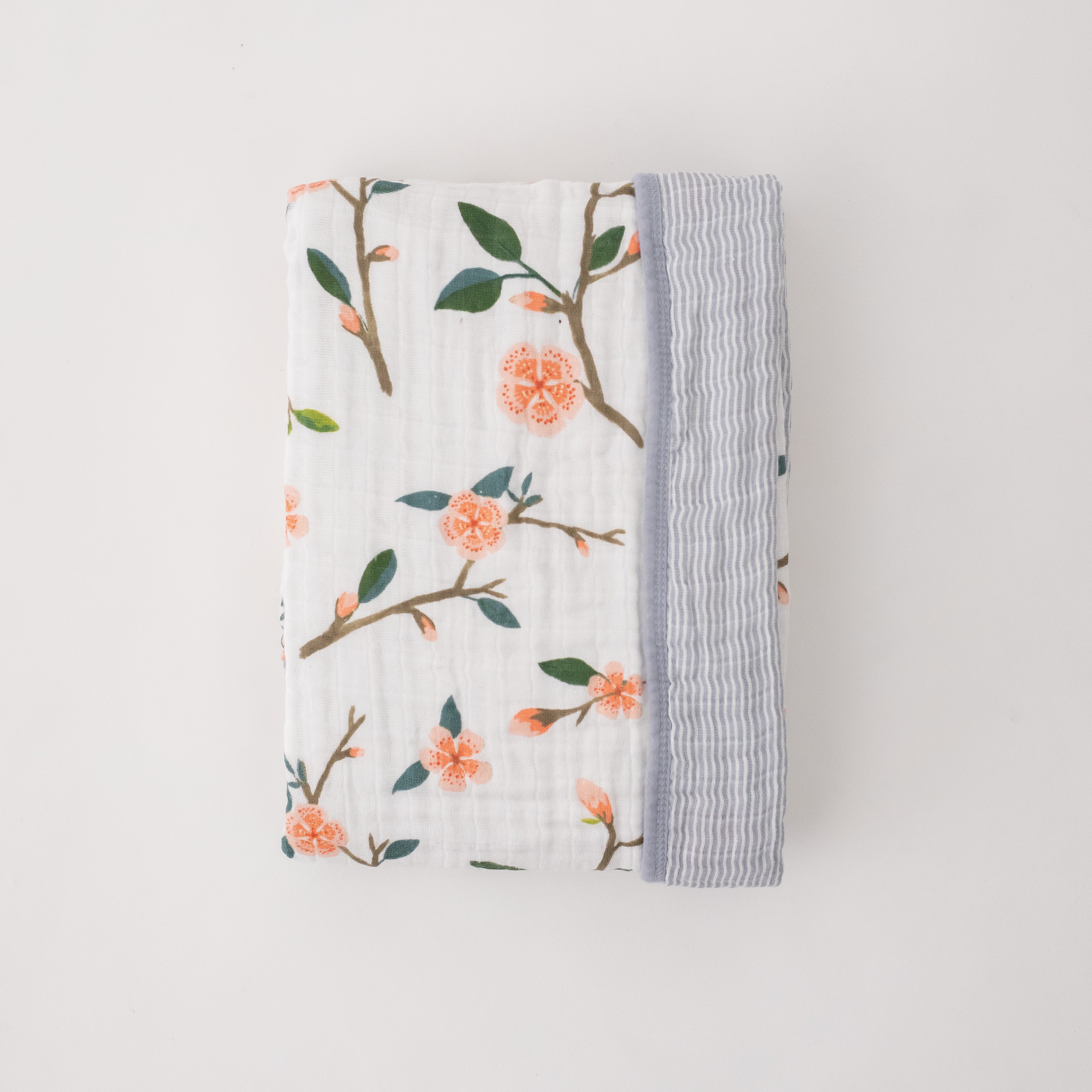 super soft cotton muslin quilt with peach blossoms blooming on a tree branch on one side and grey micro stripes on the other side