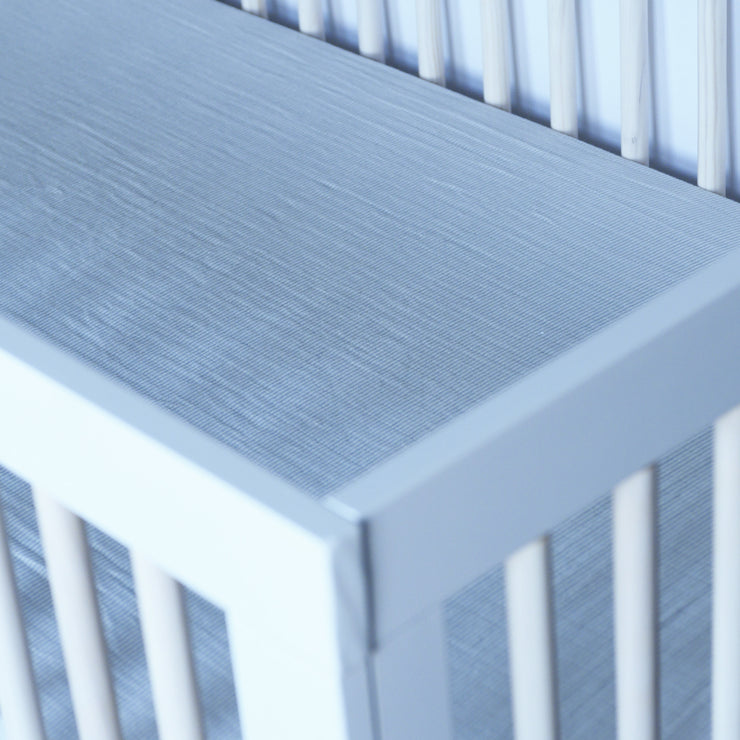 cotton muslin crib sheet with very small grey stripes in a crib