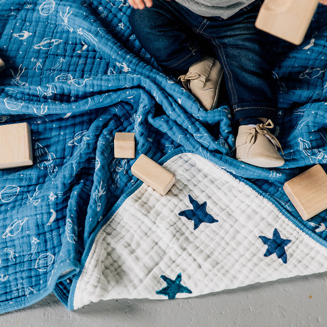 baby sitting on a sun moon stars quilt playing with blocks