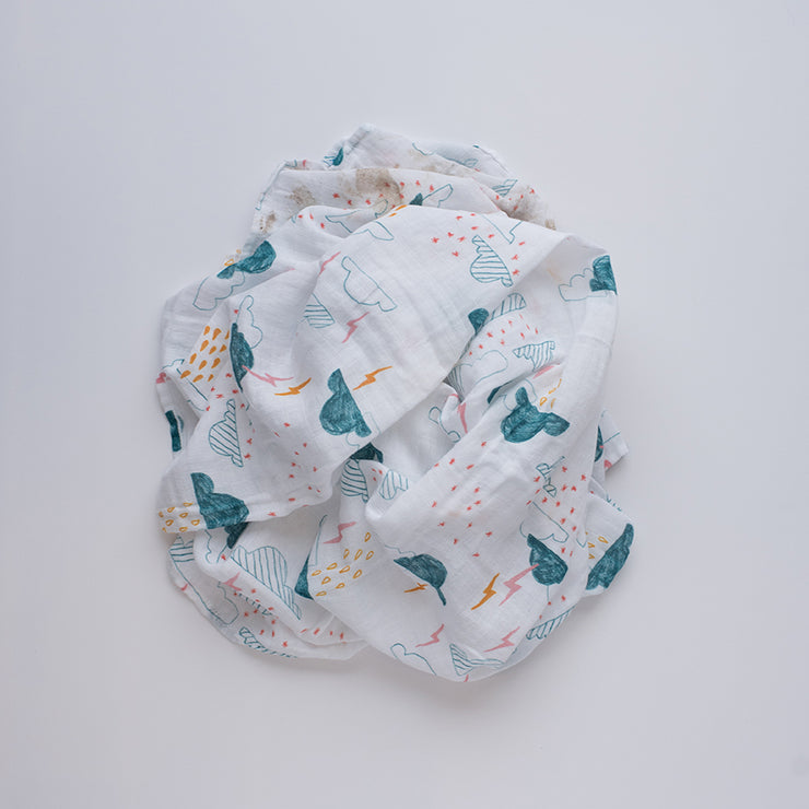 single swaddle blanket with blue clouds, yellow and pink lightening and rain