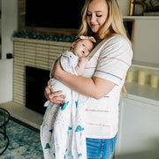 mom holding a baby wrapped with a clapping clouds single swaddle