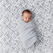 sleeping baby swaddled in a xoxo blanket laying on a love language crib sheet