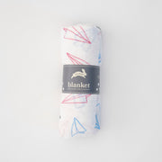 single swaddle blanket with blue, red, and grey paper planes on a white background rolled in Red Rover packaging