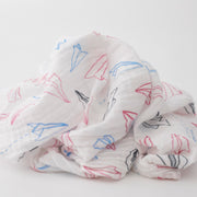 single swaddle blanket with blue, red, and grey paper planes on a white background