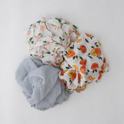 3 swaddle blankets featuring peach blossoms, whole and cut open peaches, and grey micro stripes