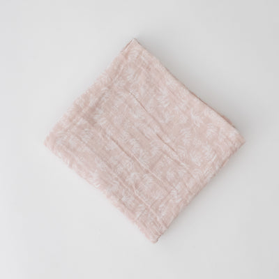 single swaddle blanket with small white flowers on a blush pink background