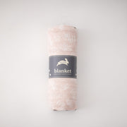single swaddle blanket with small white flowers on a blush pink background rolled in Red Rover packaging