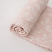single swaddle blanket with small white flowers on a blush pink background