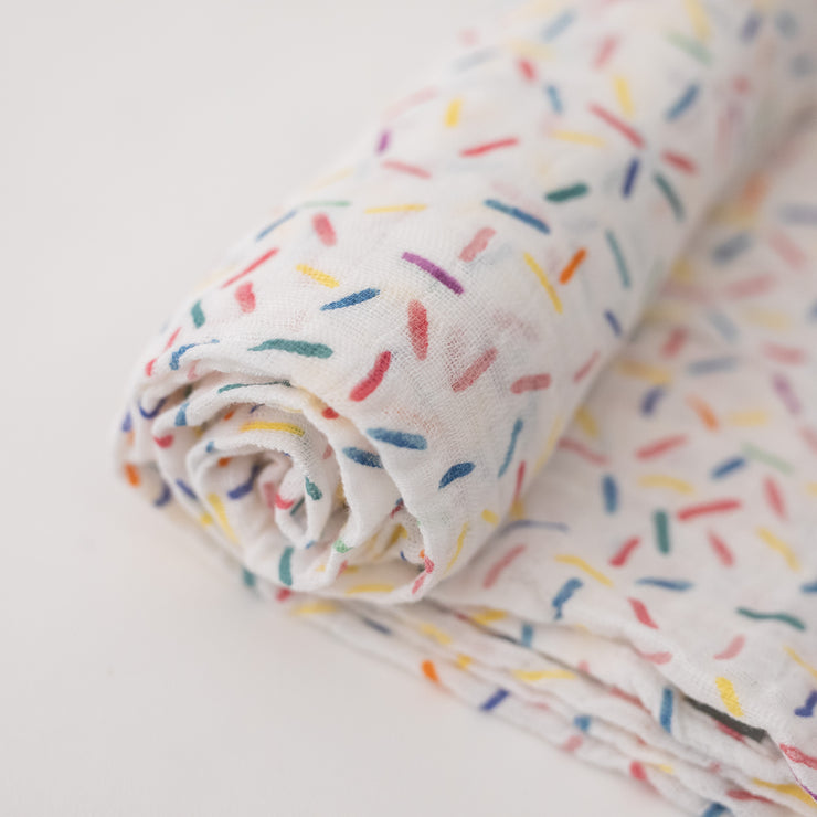 single swaddle blanket with lots of different colored sprinkles on a white background