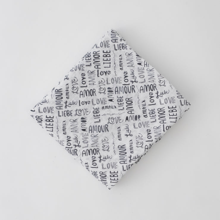 single swaddle blanket with the word "love" in multiple different languages in grey writing