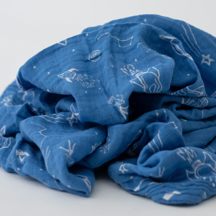 single swaddle blanket with white starts, telescopes, rocket ships, and planets all on a blue background