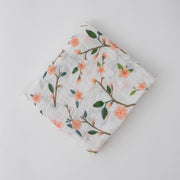 single swaddle blanket with peach blossoms blooming from a tree branch
