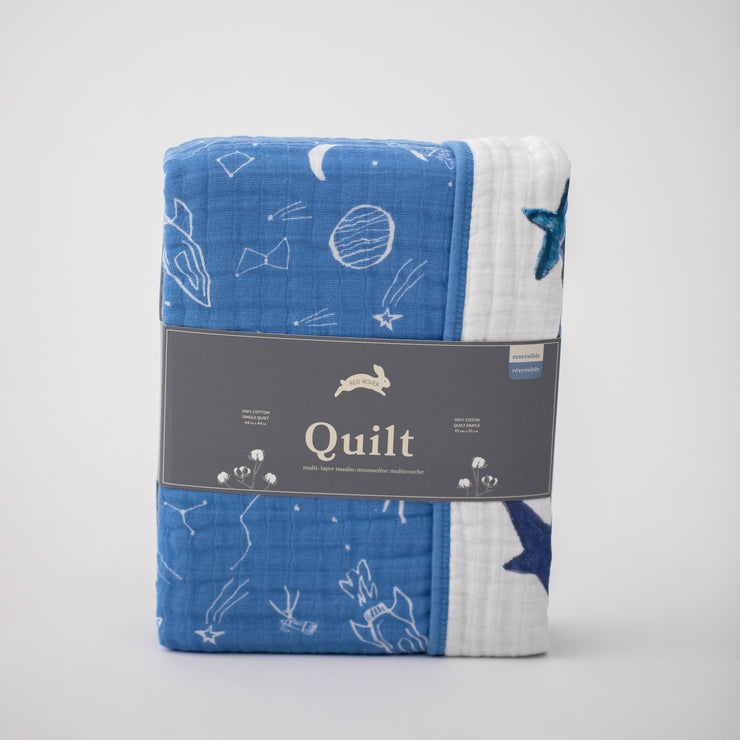 super soft cotton muslin quilt with white planets, stars, telescopes, and rocket ships all on a blue background on one side and the text "you are my sun my moon and all my stars" on the other side in Red Rover packaging