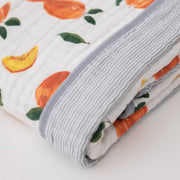 super soft cotton muslin quilt with whole and cut open peaches on one side and grey micro stripes on the other side