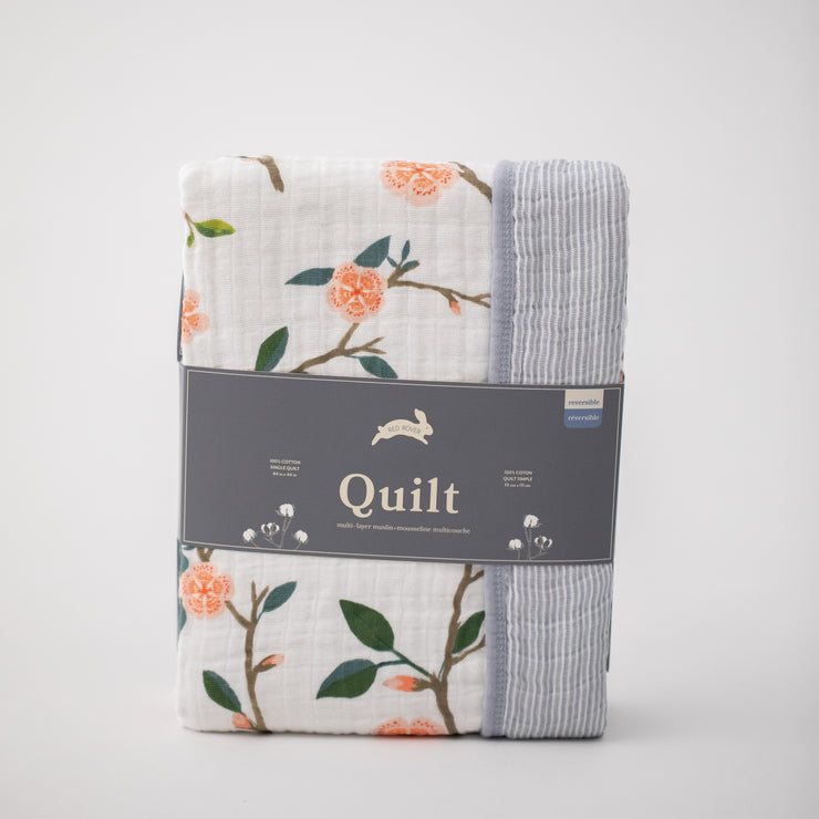 super soft cotton muslin quilt with peach blossoms blooming on a tree branch on one side and grey micro stripes on the other side in Red Rover packaging