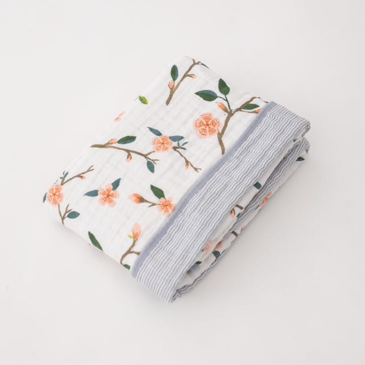 super soft cotton muslin quilt with peach blossoms blooming on a tree branch on one side and grey micro stripes on the other side