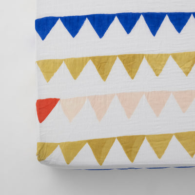 cotton muslin crib sheet with yellow and blue triangles strung together like a party banner