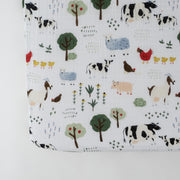 cotton muslin crib sheet with farm animals including cows, chickens, goats, sheep, and pigs