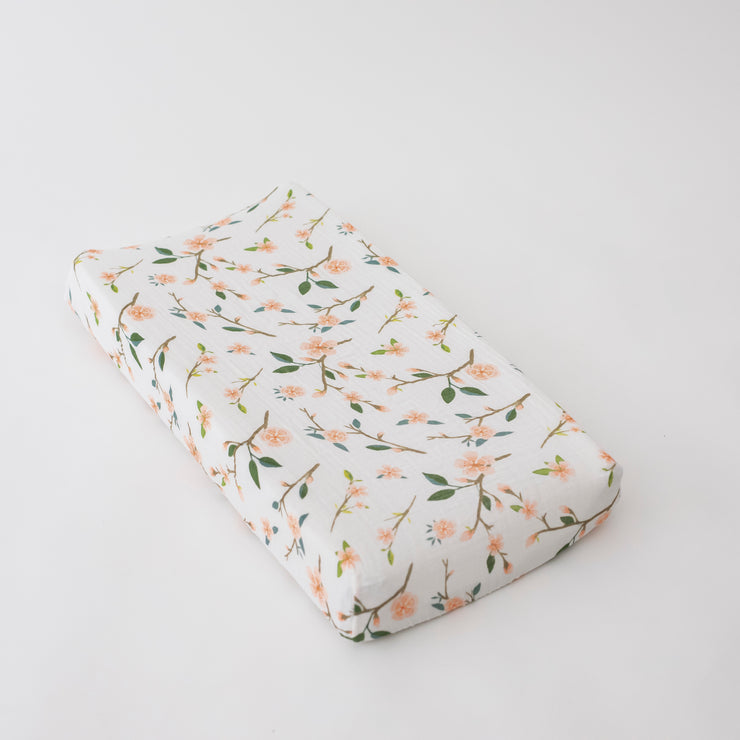 cotton muslin changing pad cover with pink peach blossoms blooming on a branch with leaves